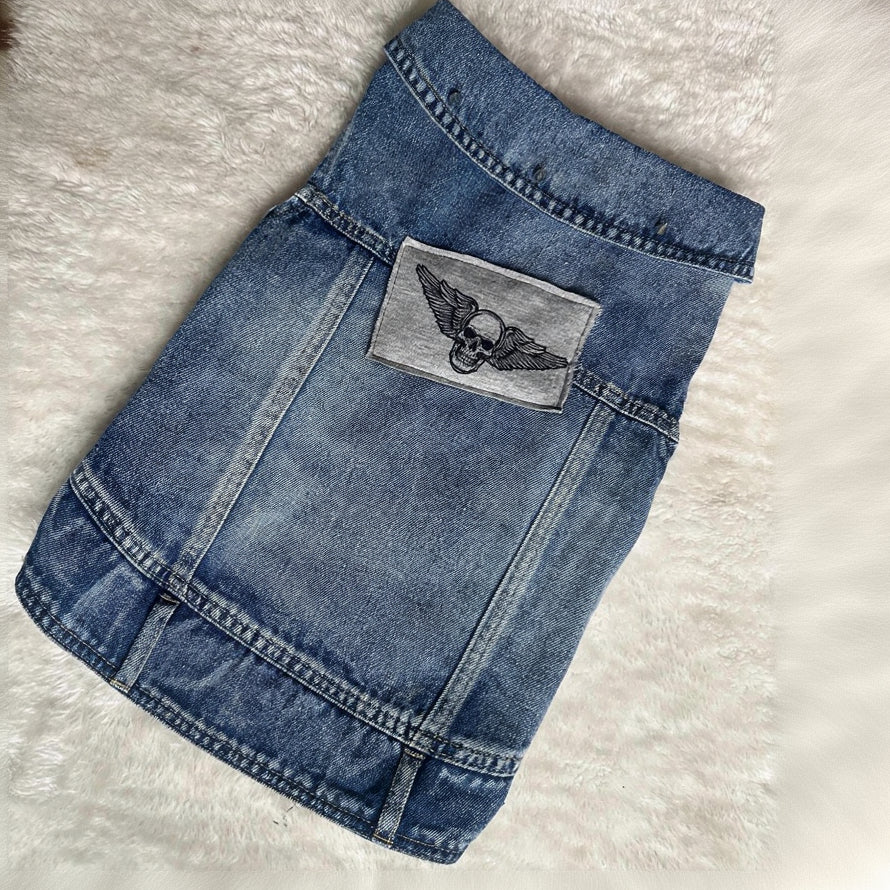 Blue denim skirt with a gray patch featuring wings on a light gray background