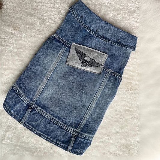 Blue denim skirt with a gray patch featuring wings on a light gray background