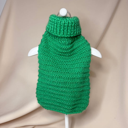 Green knitted dog sweater on a hanger against a beige background